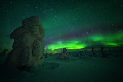 在北极光的夜晚被雪覆盖的石堆